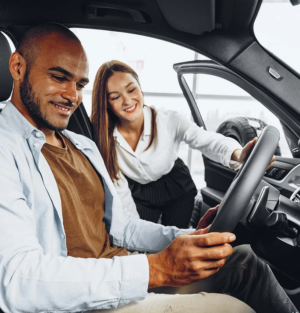 salesperson showing another person car who is sitting in it