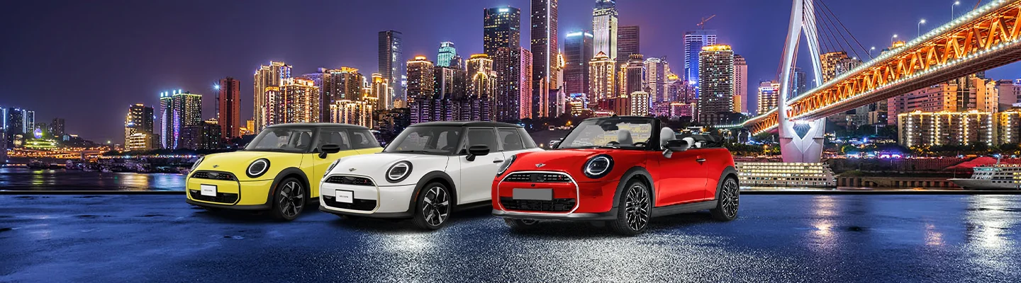 Three MINI models lined up in a row in front of a city skyline