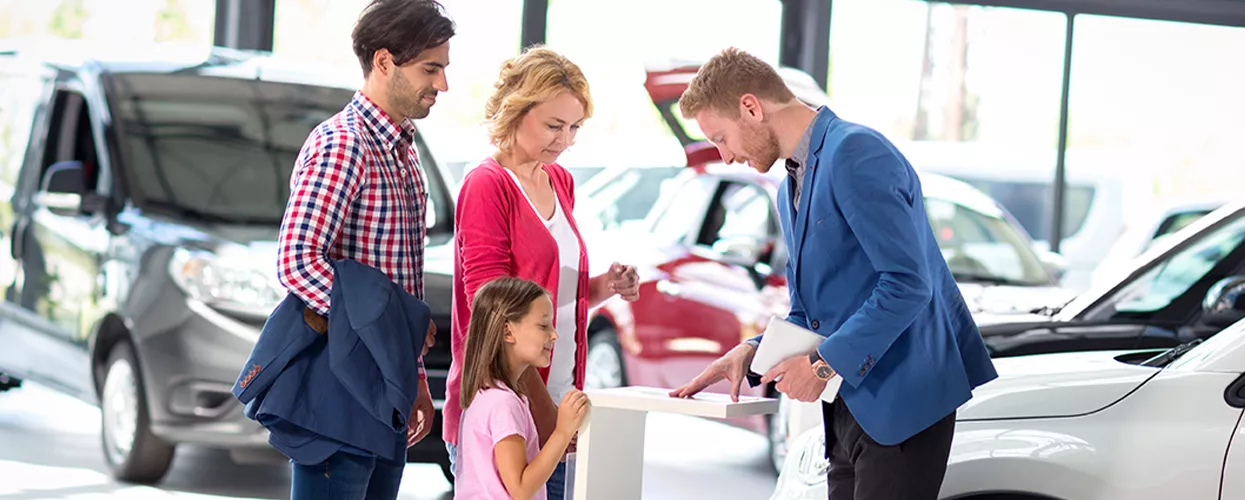 Car salesman showing a family a new vehicle at a car dealership