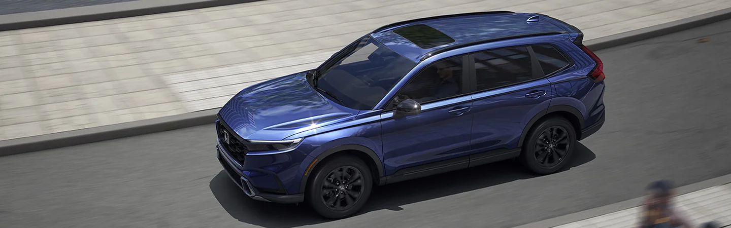 silver 2025 Honda CR-V Hybrid Sport coming around a mountain curve in motion