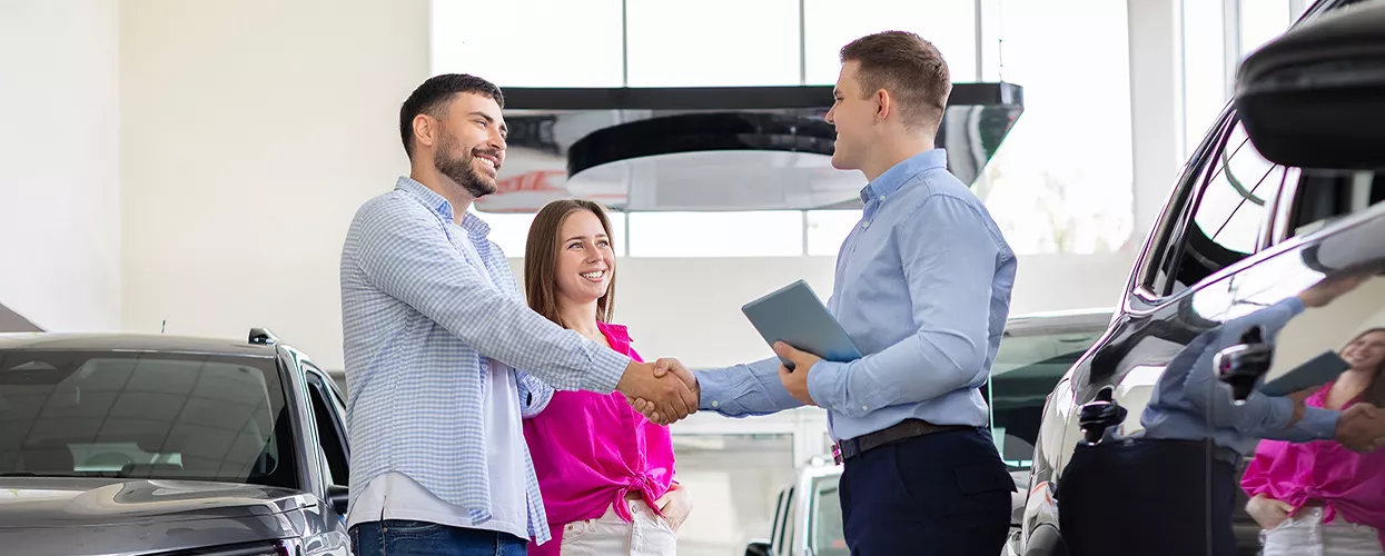 Couple shaking hands with a car salesman