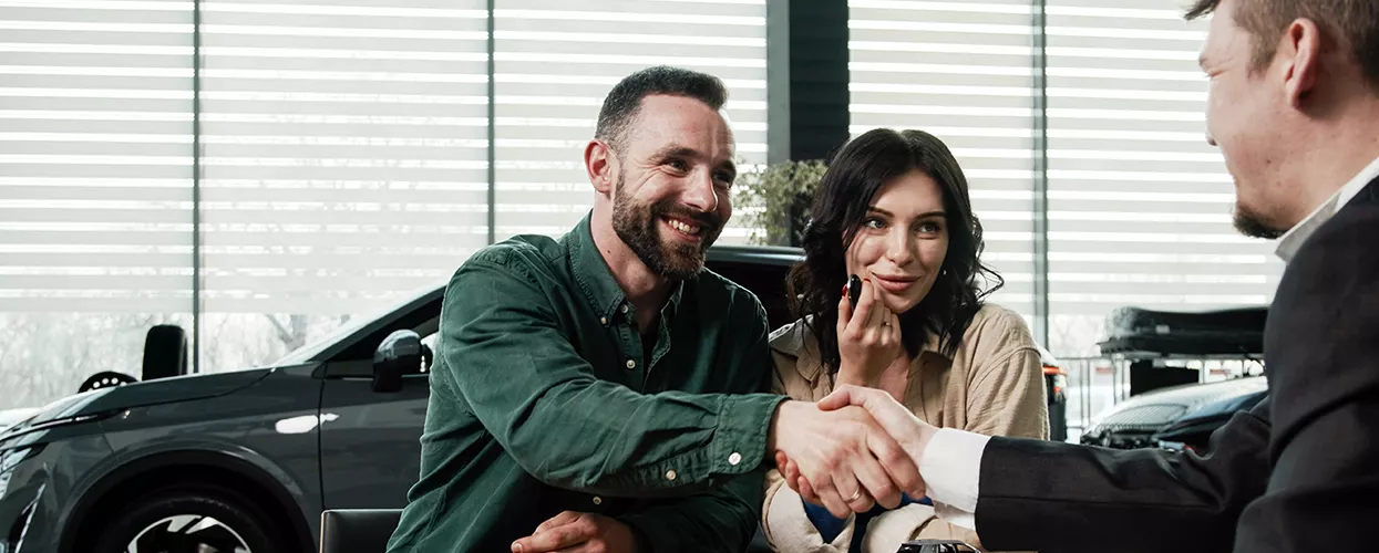 Car salesman talking to a couple about a new vehicle