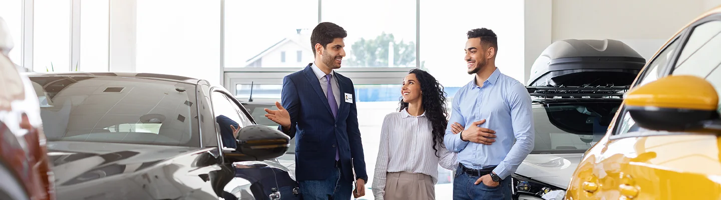 Car salesman showing vehicle to customers