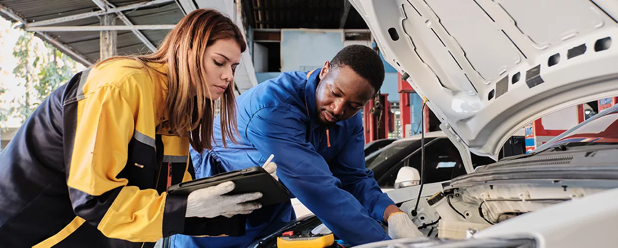 Service mechanics working under the hood of a vehicle