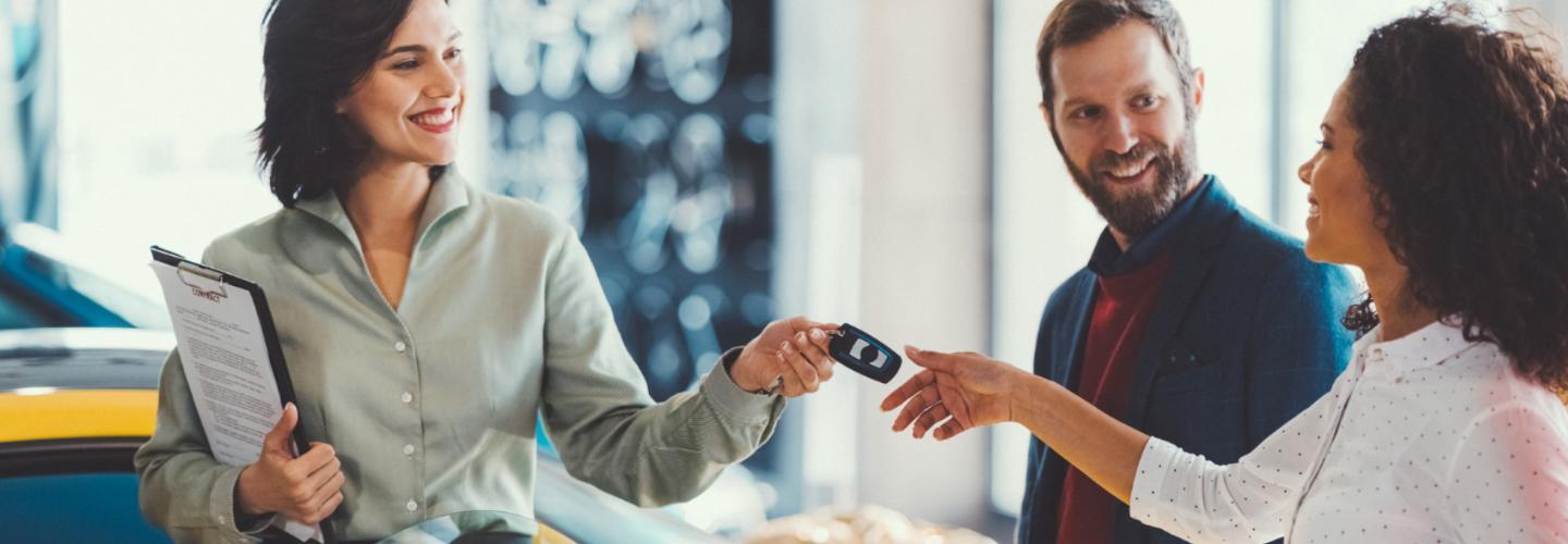 A dealership employee handing car keys to a customer