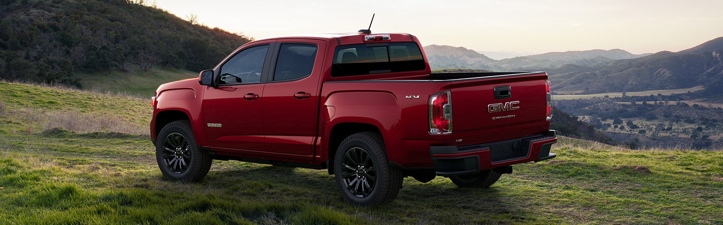 Side view of a red 2022 GMC Canyon parked in the wilderness