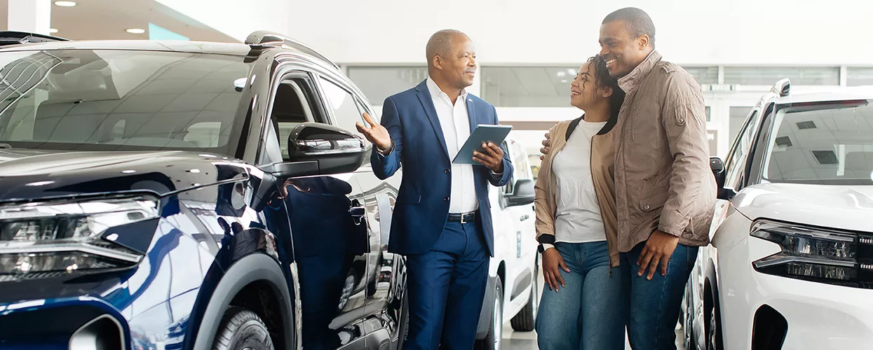 two people in car showroom speaking with salesperson