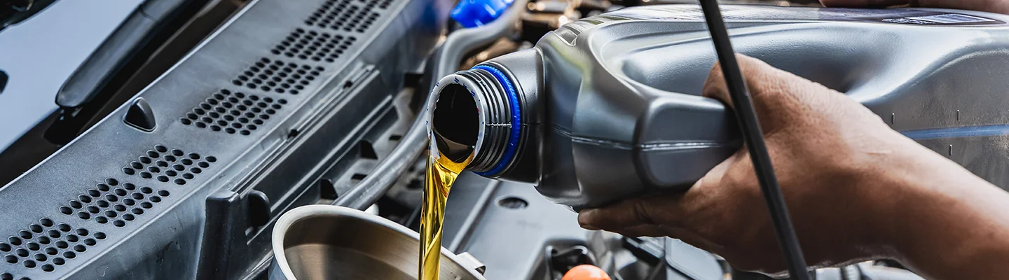 Auto mechanic pouring oil into engine
