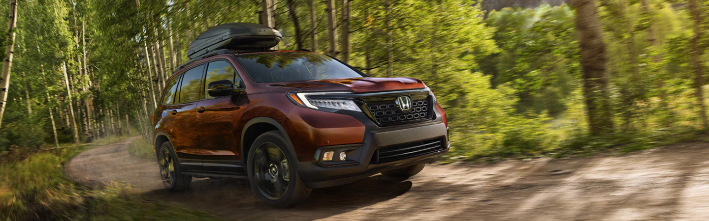 A maroon 2021 Honda Passport driving through the woods