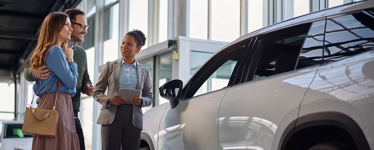Sales person showing a happy couple a nwe BMW SUV