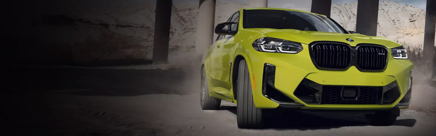 A yellow 2024 BMW X4 driving in dirt