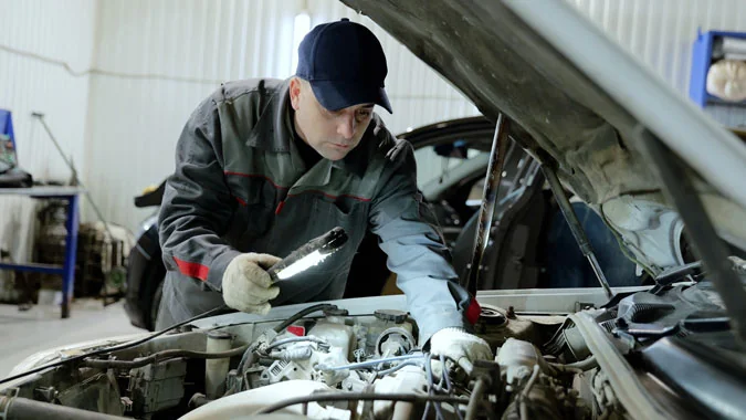 Service tech checking on the engine of a car