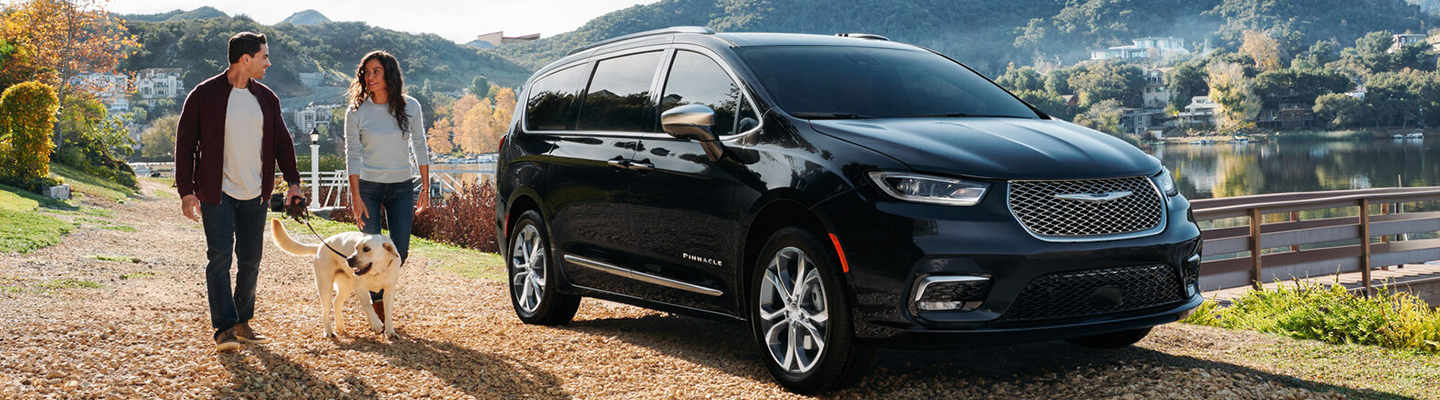 Couple walking a dog next to the 2021 Chrysler Pacifica