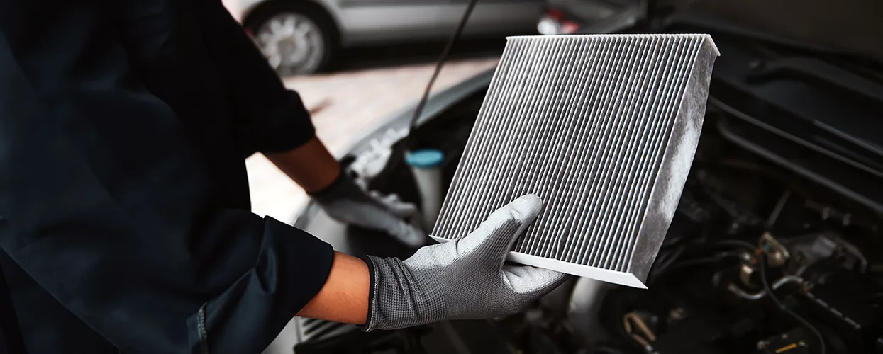 Automotive technician replacing a vehicle cabin air filter during routine maintenance service in a professional auto repair shop