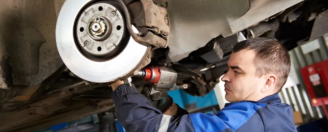 Auto mechanic working on brakes on a car up on a lift