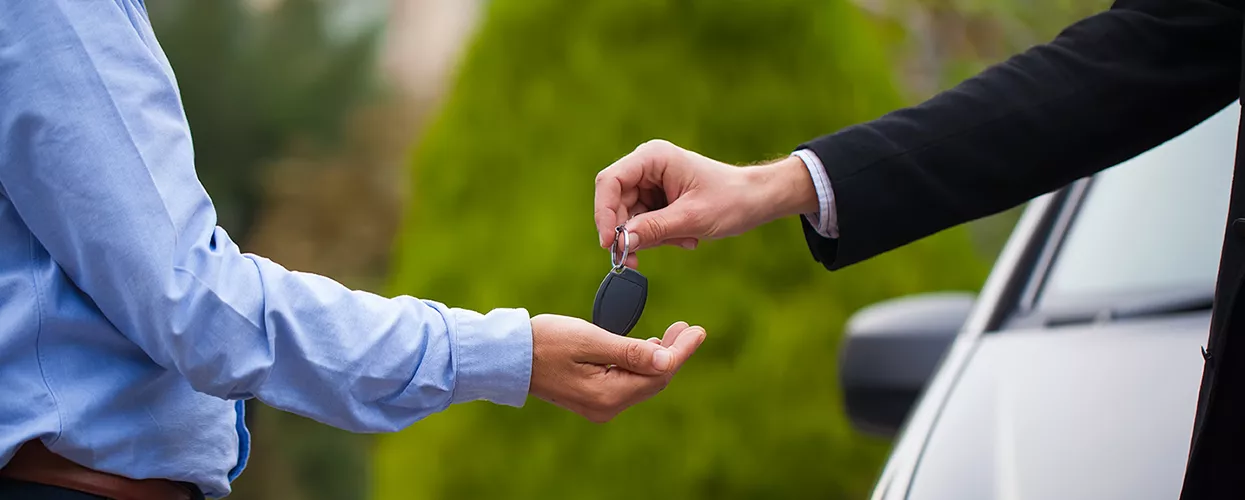 Car salesman handing a customer a new set of car keys