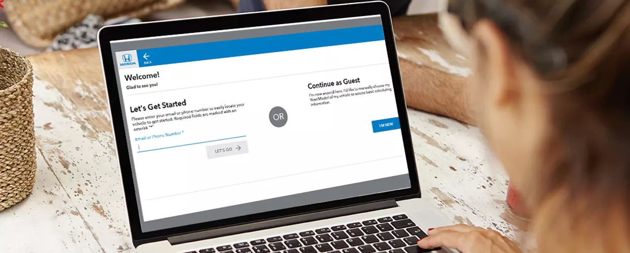 Customer using an online dealership service scheduling tool on a laptop to book vehicle maintenance and repair appointments