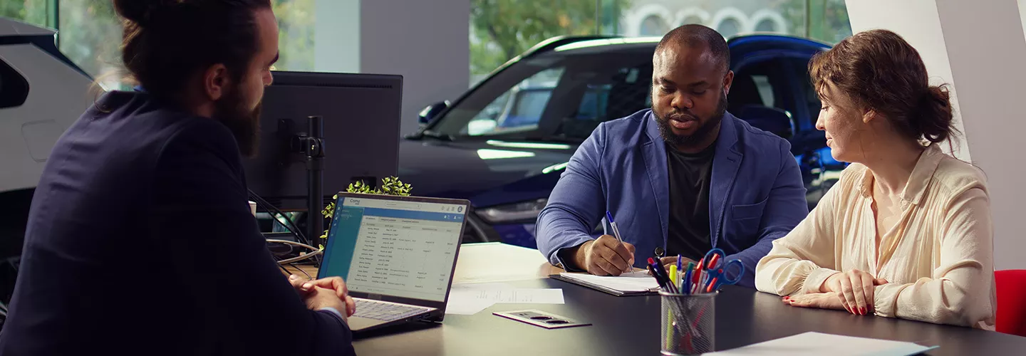 Car salesman talking to two people about a contract