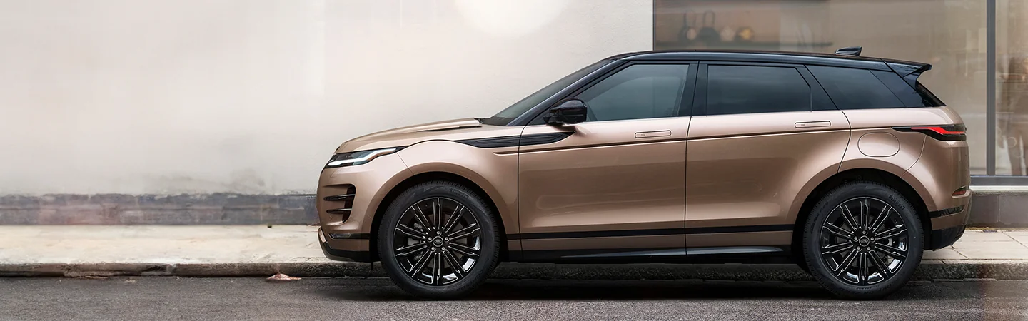 Side view of a parked copper 2026 Range Rover Evoque in front of a building