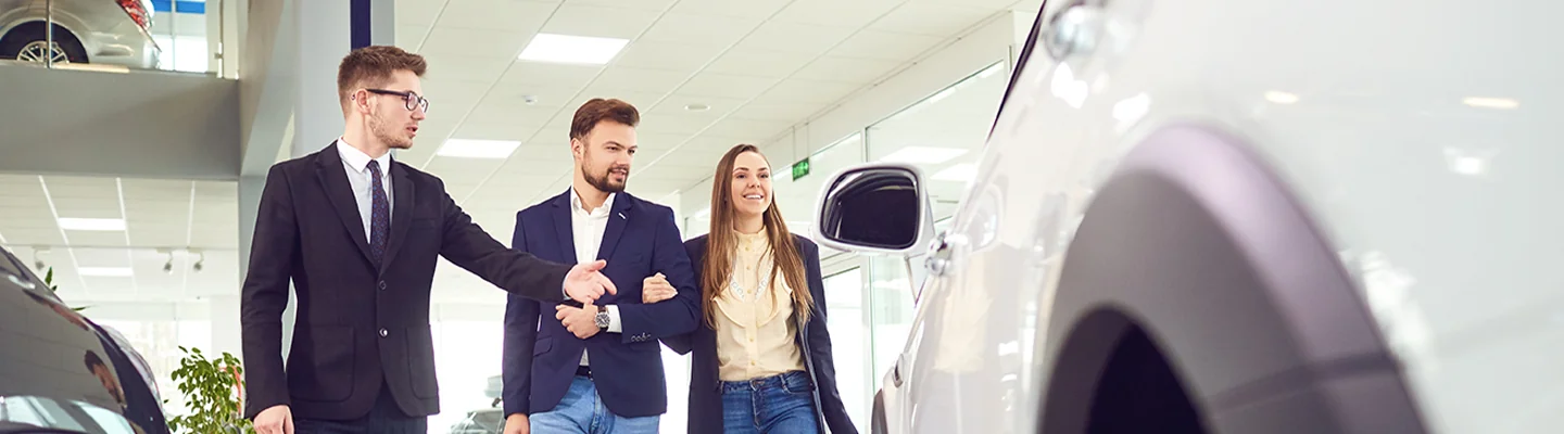 two people looking at car with a salesperson in the dealership showroom in Leesburg FL