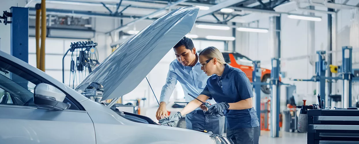 Service mechanic working under the hood of a vehicle