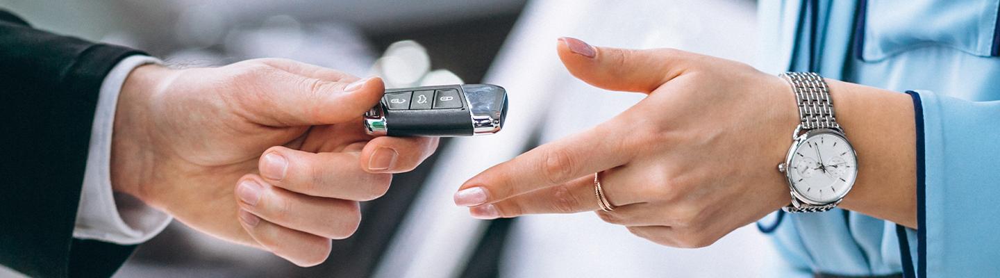 A dealership employee and customer exchanging car keys