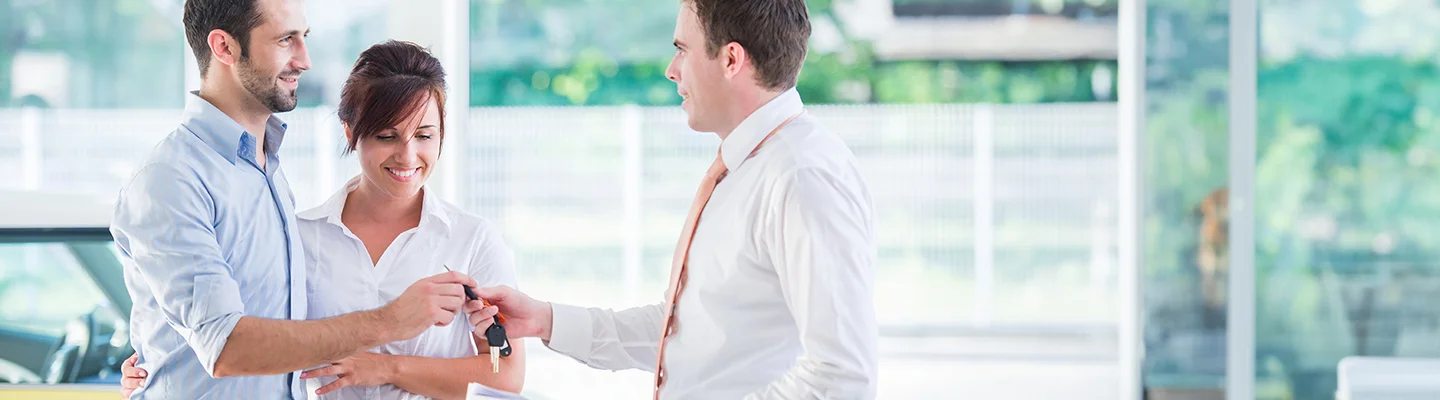 Couple buying car from salesperson in showroom