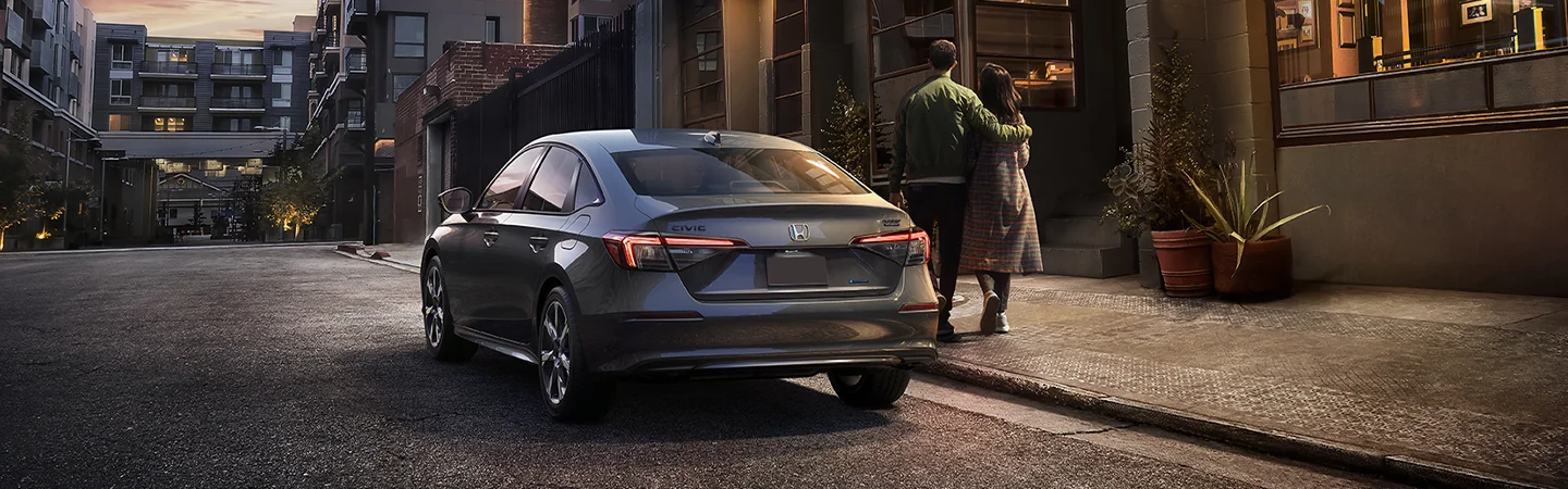Back view of a gray 2026 Honda Civic parked on a city street by apartments