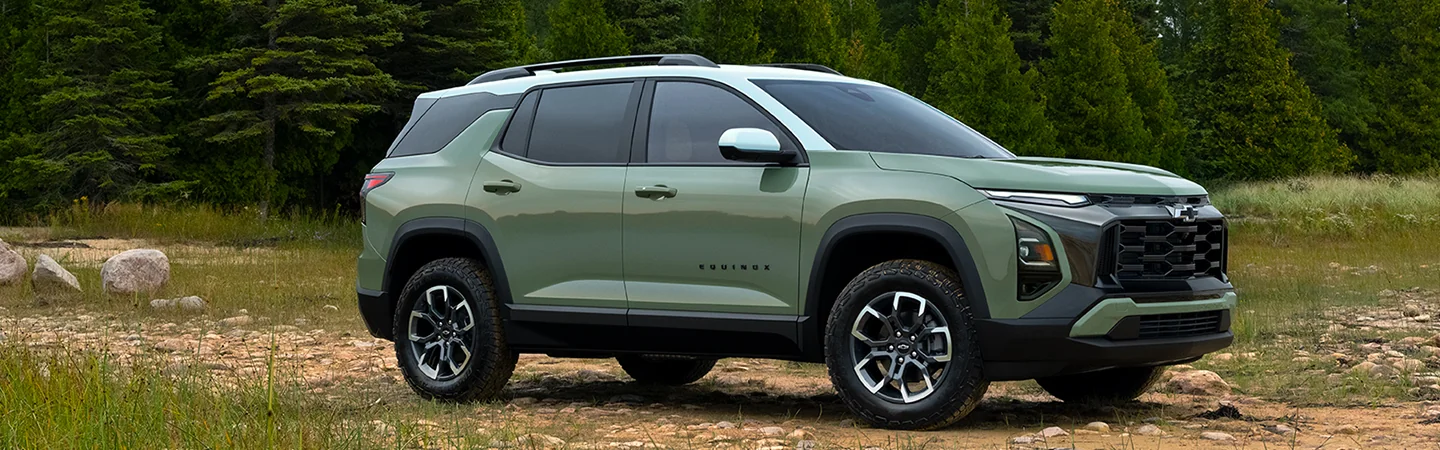 Front side view of a parked green 2025 Chevrolet Equinox in the woods
