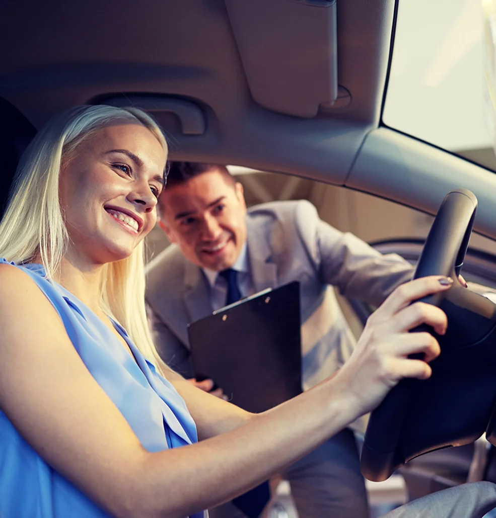 A man and woman sit in a car, both smiling and enjoying their time together.