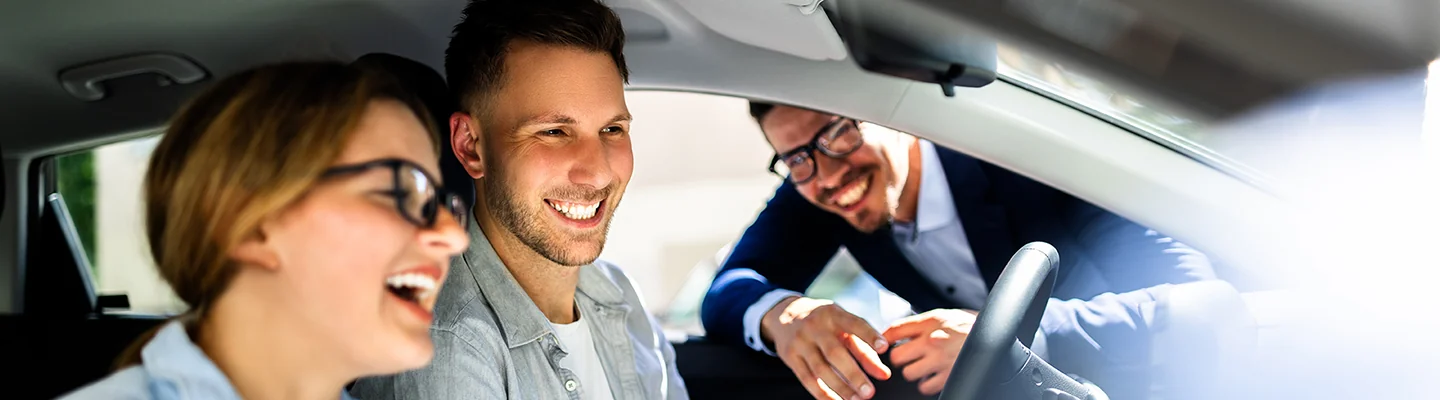 salesman talking to a couple through the window inside a vehicle