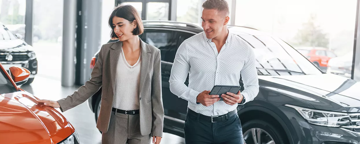 a person looking over a car with salesperson in showroom