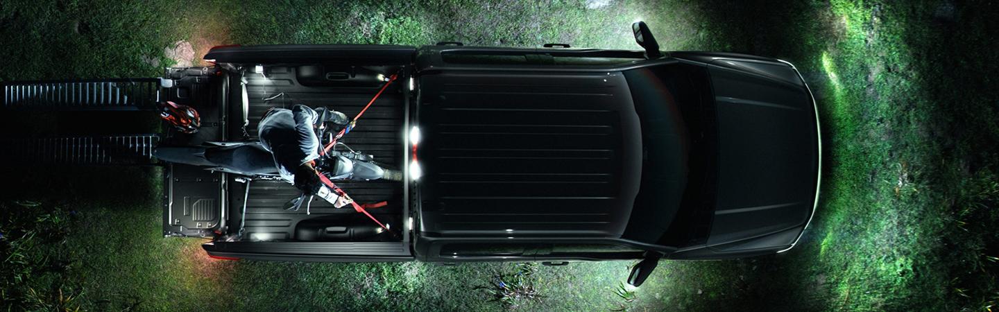Bird's eye view of black 2022 Ford F-150 Lightning at night with dirt bike in bed of trunk