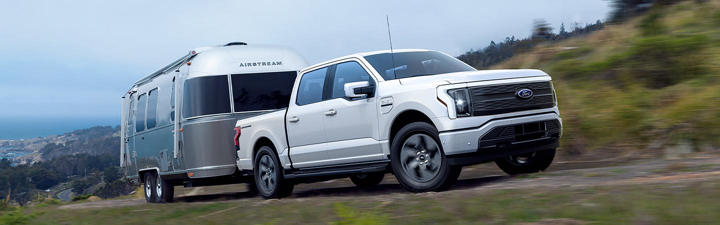 White 2021 Ford F-150 towing camper on dirt road