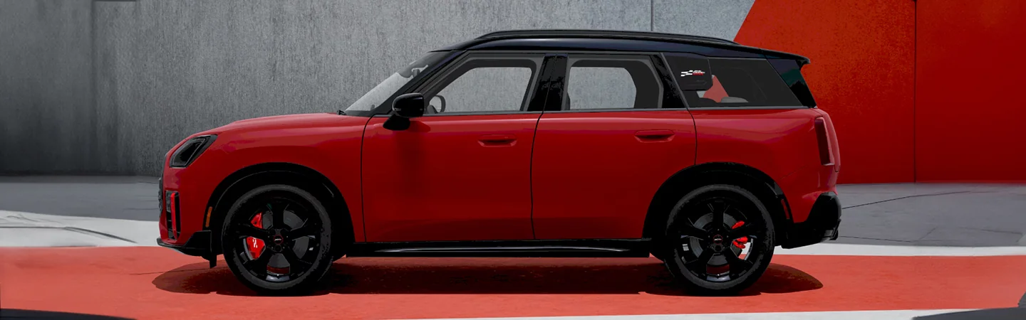 Side view of a parked red 2025 JCW Countryman ALL4 in a show room