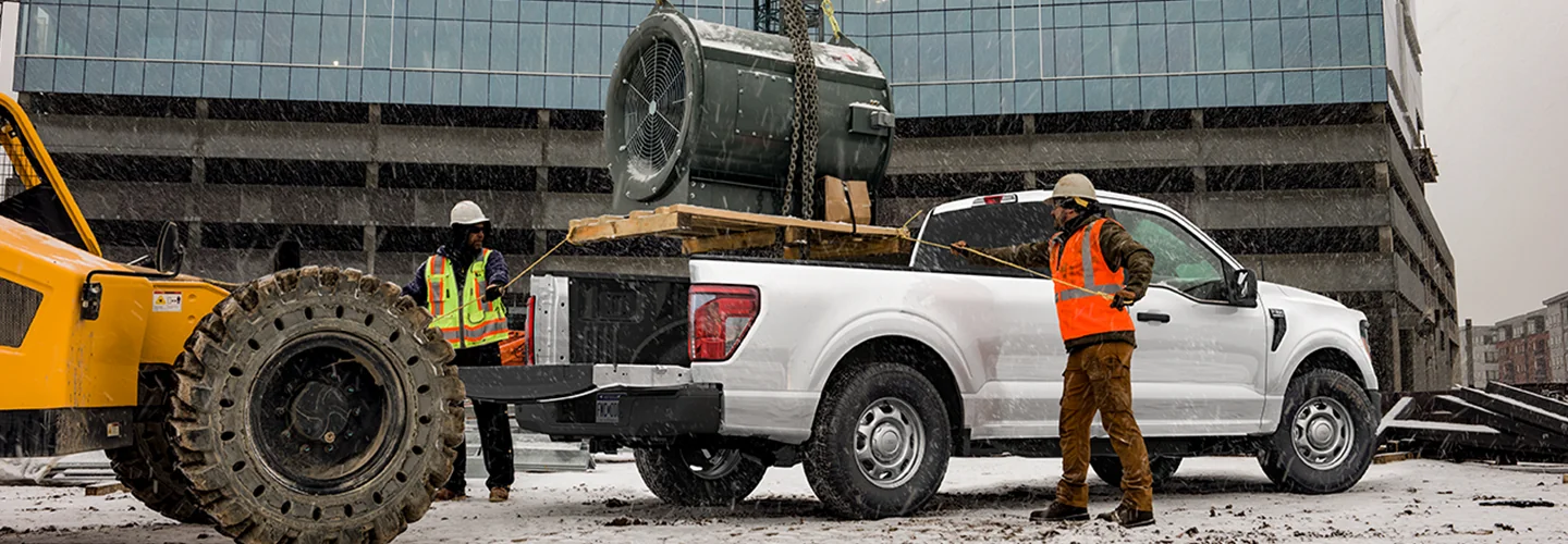 Workers putting something inside the bed of a Ford work truck