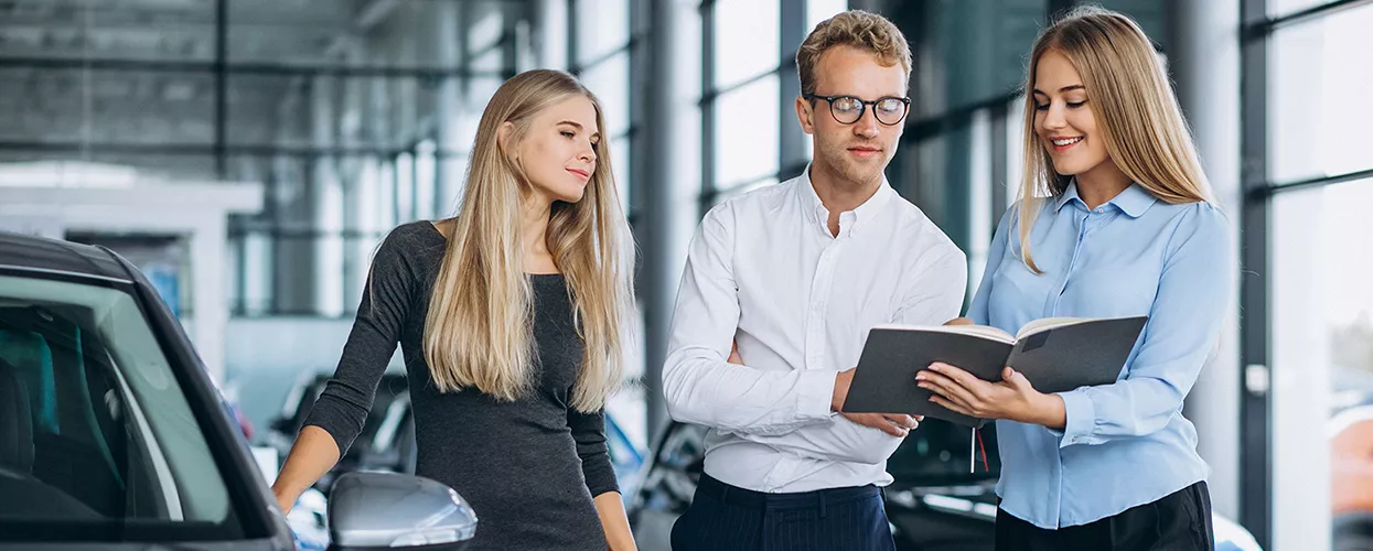 Customer reviewing finance and lease paperwork with a BMW advisor at a dealership