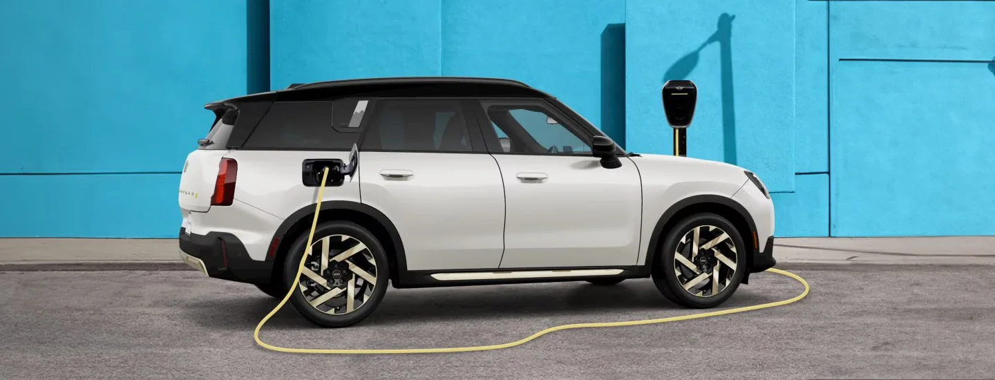 A white 2025 MINI Countryman SE ALL4 parked getting charged