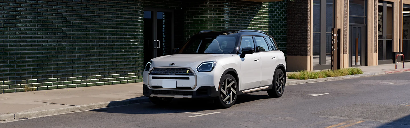 A whtie parked 2025 MINI Countryman SE ALL4 in front of a buliding