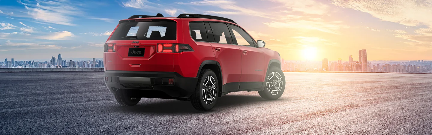 Back view of a red 2026 Jeep Cherokee parked with a city in the background
