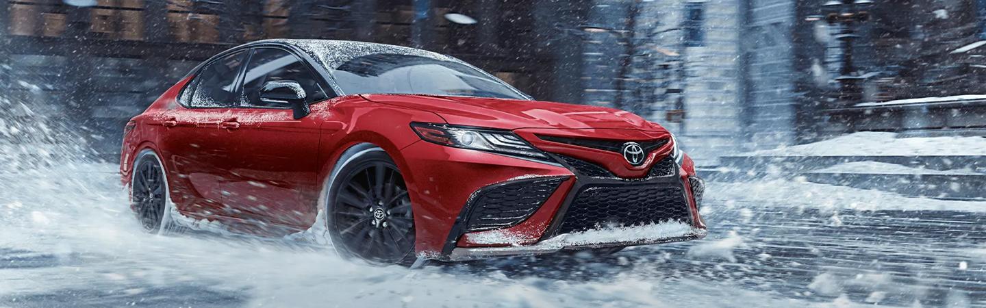 red 2021 Toyota Camry drving on snowy city street