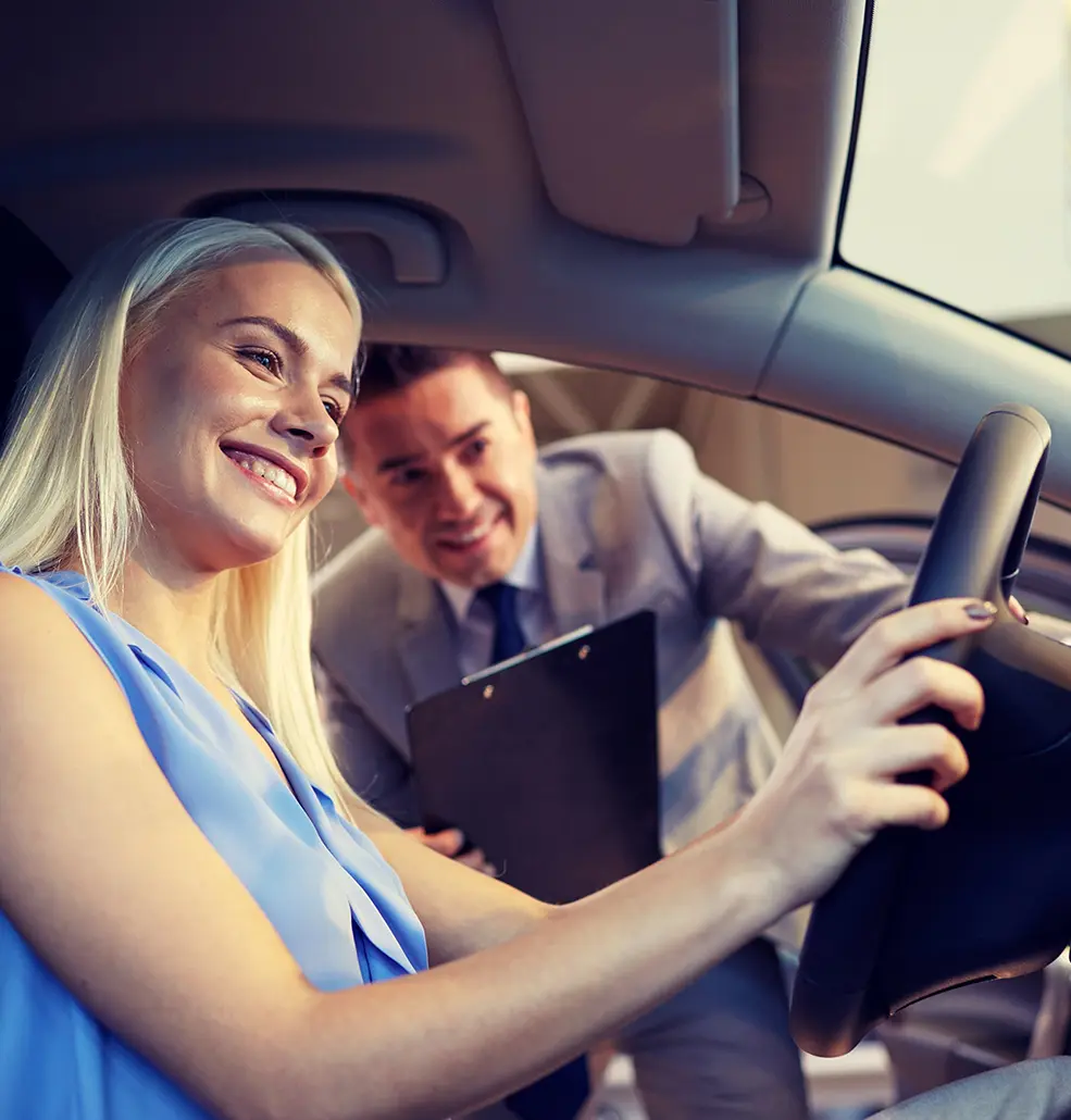 man and customer examining inside of new car in car showroom