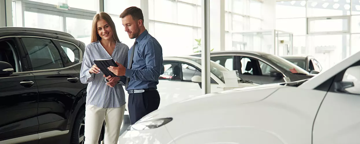 Car salesman showing a customer a vehicle in a kia dealership