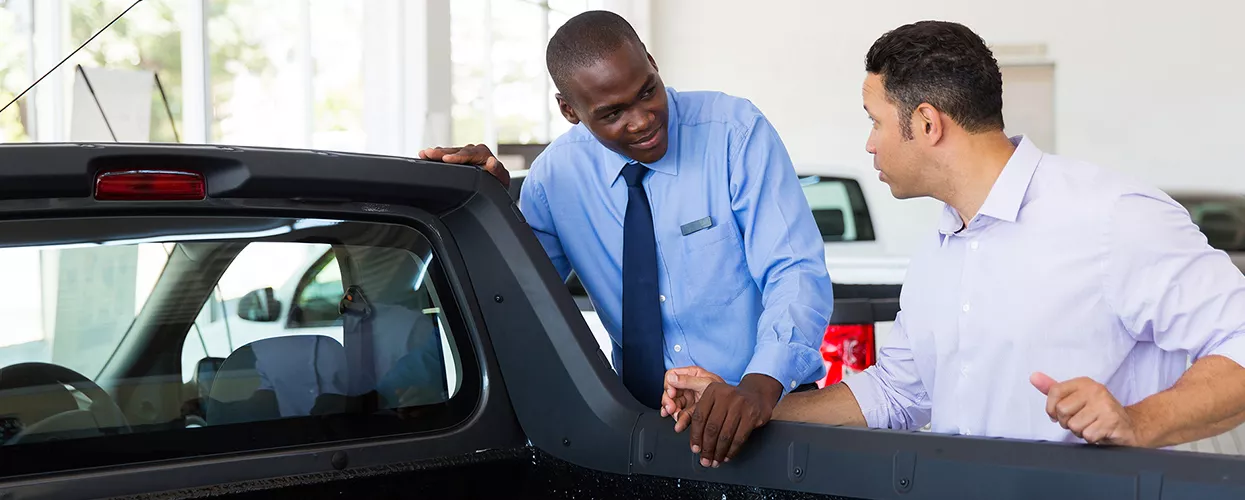 Car salesman showing a customer a truck in a dealership