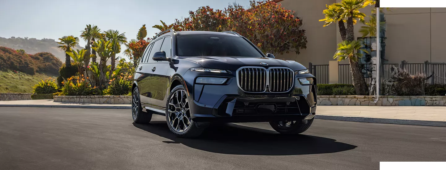 2026 BMW X7 parked in front of a home with palm trees in the background in the daytime