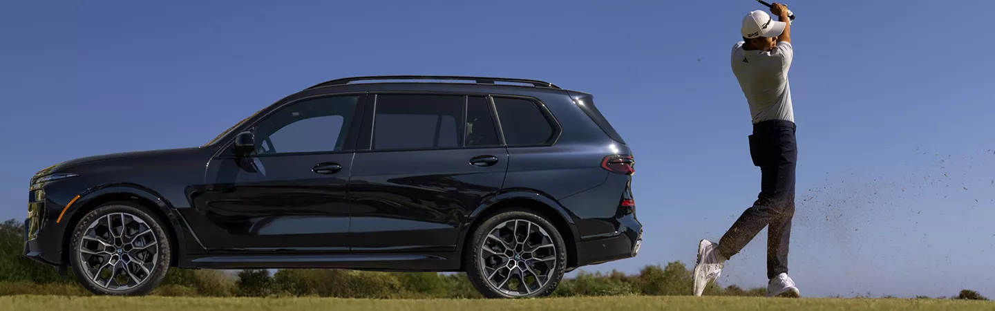 Man swinging golf club next to a parked 2026 BMW X7