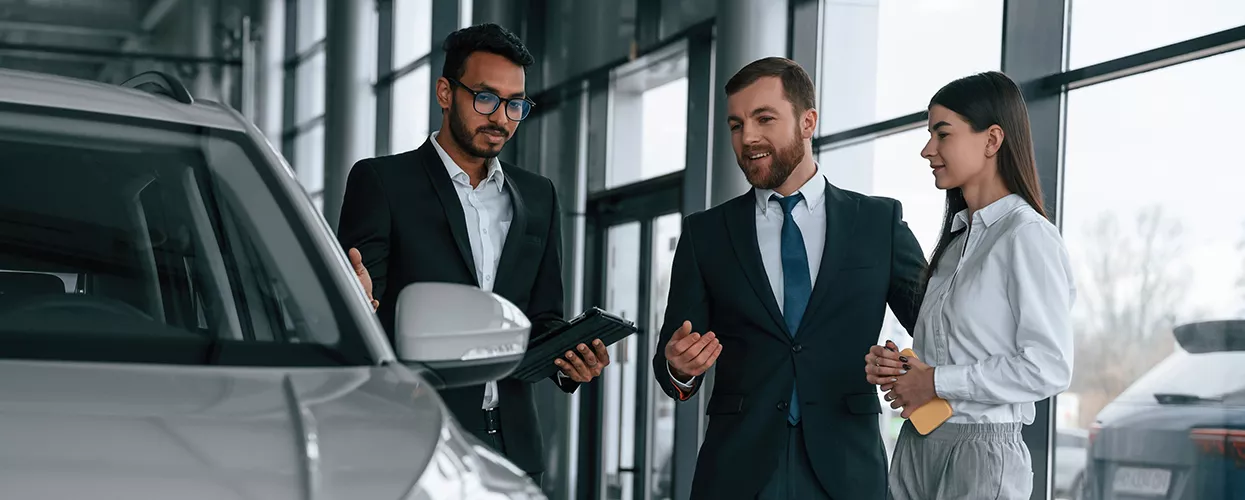 Two people looking at a vehicle with a car salesman