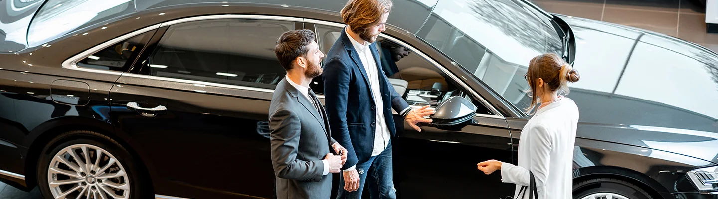 top view of a couple looking over car with salesperson in the showroom