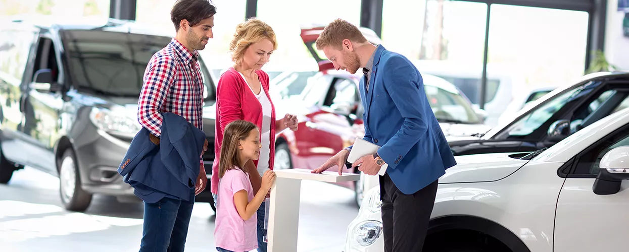 family of three speaking with the car salesperson in  dealership