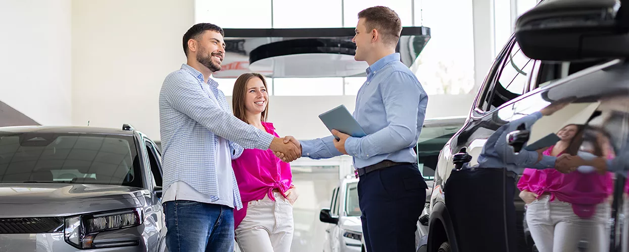 Two people shaking hands with a car salesmna in a Toyota dealership